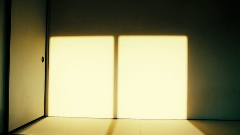 淡い畳の床と漆喰の壁に、午後の日ざしが三つの明るい四角形になって落ちている