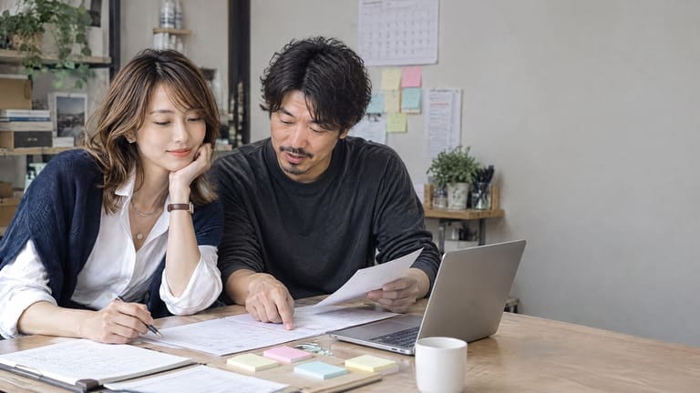 ノートパソコンと資料を囲んで相談する二人