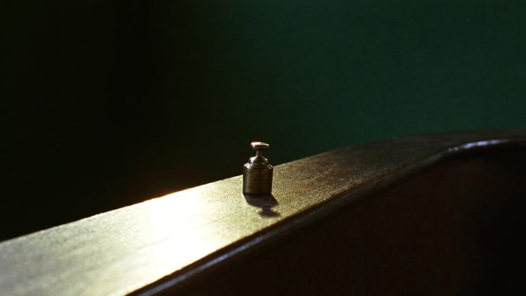 使い込まれて艶の出た木のカウンターの縁に光が一筋差し、真鍮の重しがひとつ置かれている